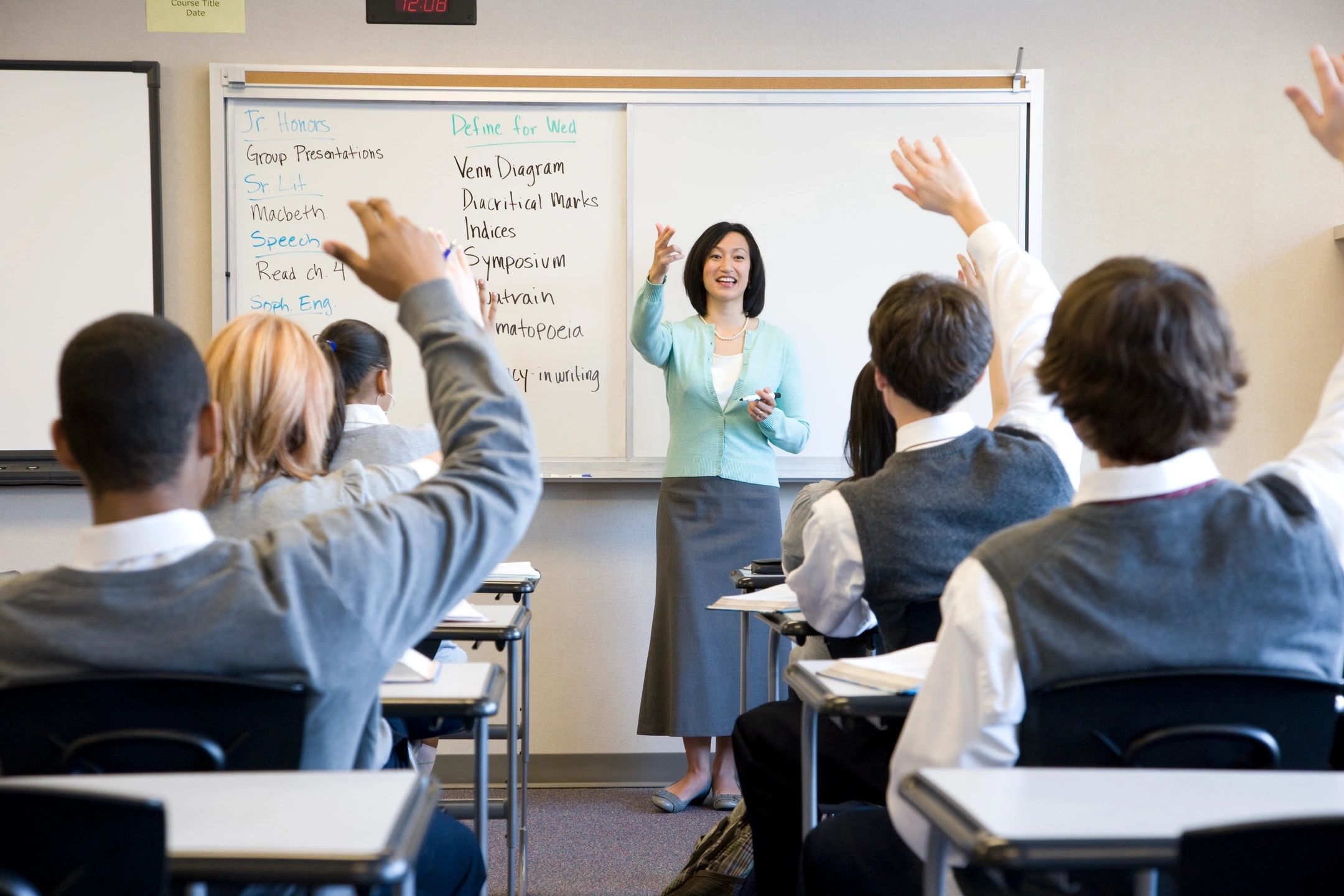 UK Boarding School students raising their hands in class